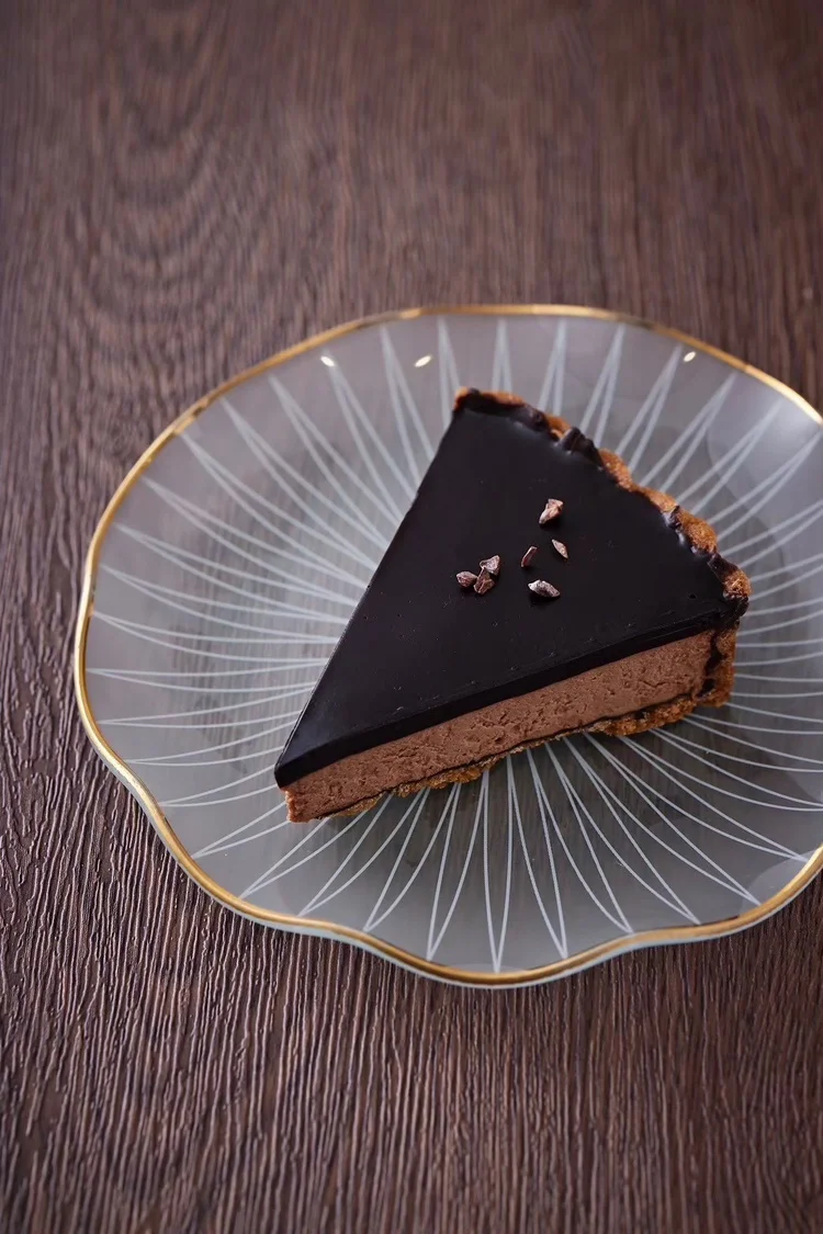 ガラスの皿にのせたチョコレート色のケーキ