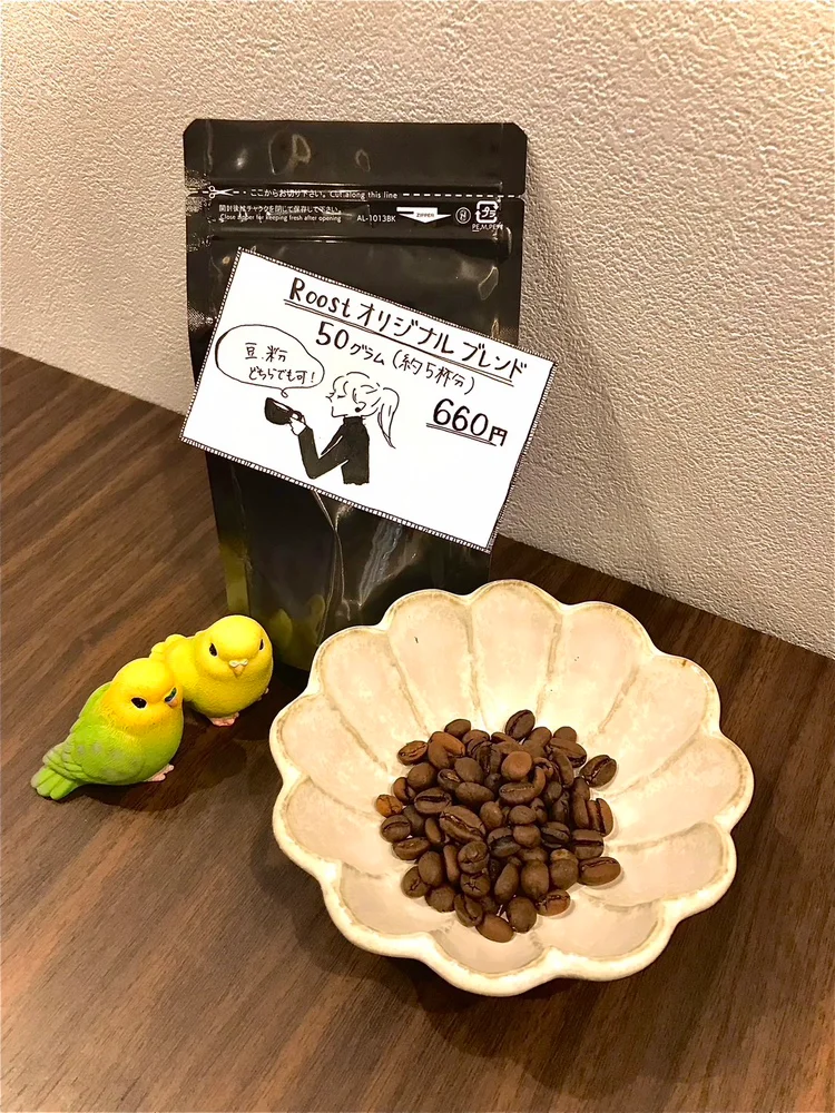 鳥の置物と一緒に並んだコーヒー豆と袋